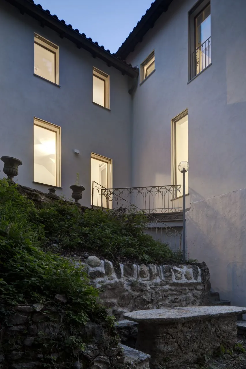 La casa di Senago al crepuscolo, finestre illuminate sopra il giardino terrazzato in pietra