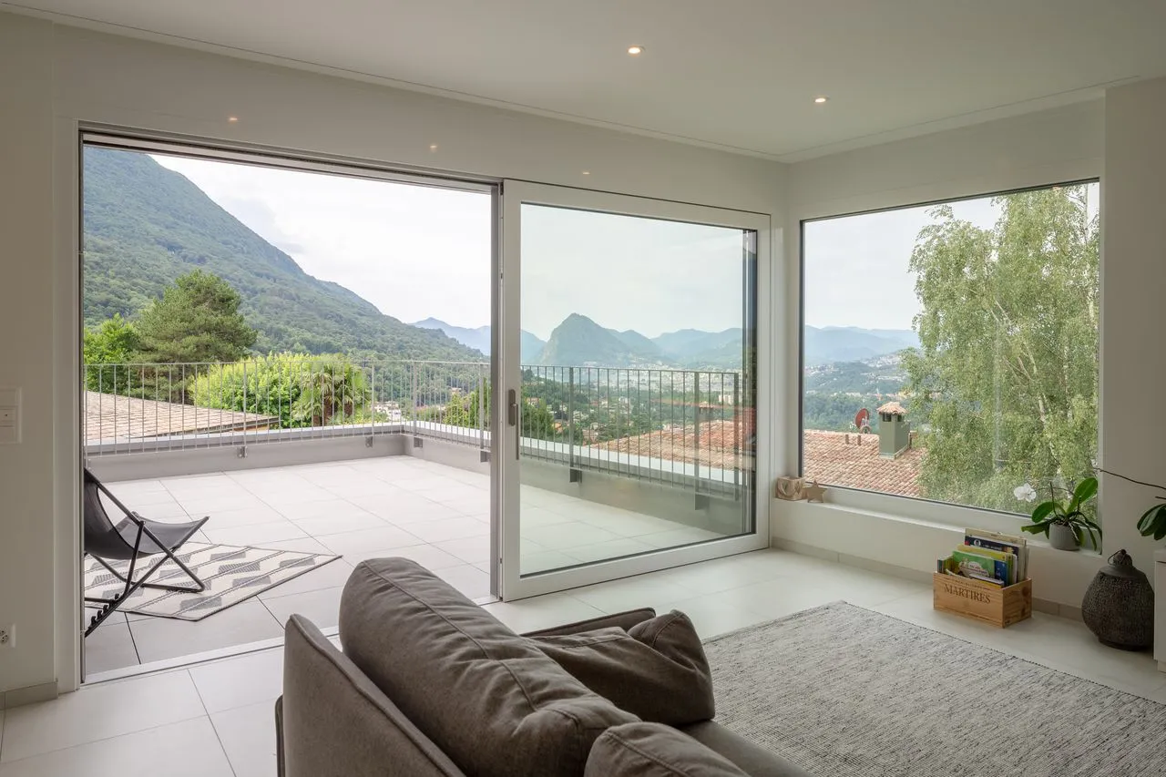 Soggiorno con vetrate d'angolo sulla terrazza e vista sul lago e sulle montagne