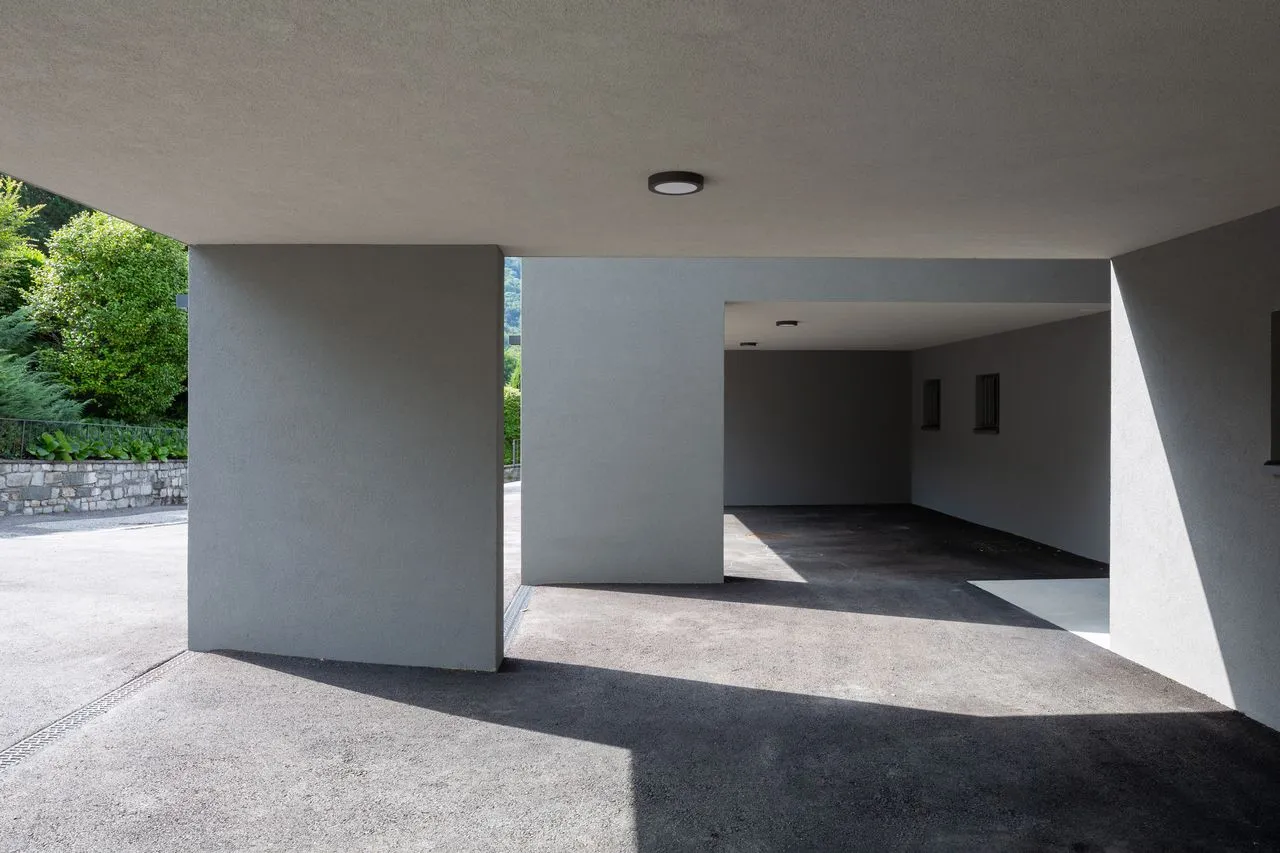 Portico coperto in calcestruzzo chiaro aperto sul giardino